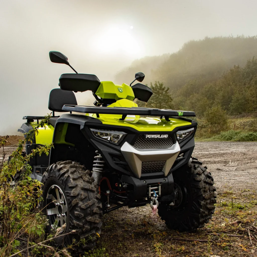 Elektrisk Powerland ATV på en mudret off-road bane med en tåget skov i baggrunden